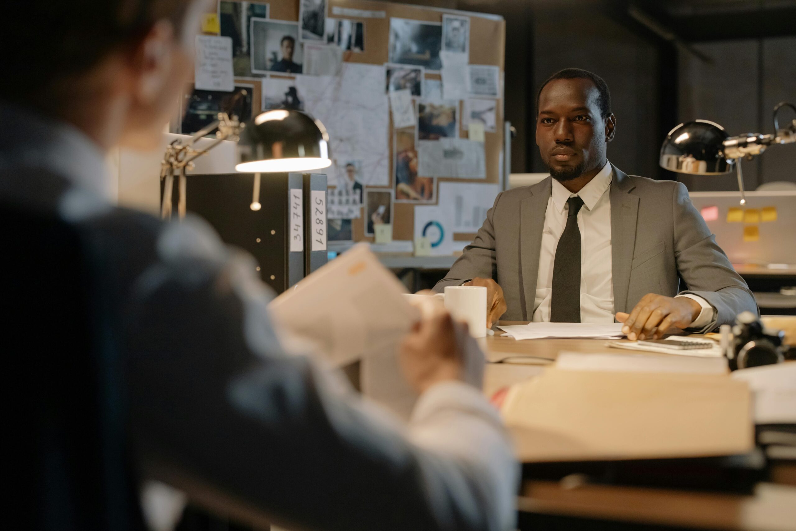 A serious workplace investigation meeting, with a professional in a suit listening attentively across a desk, highlighting the importance of maintaining psychological safety during the investigation process.